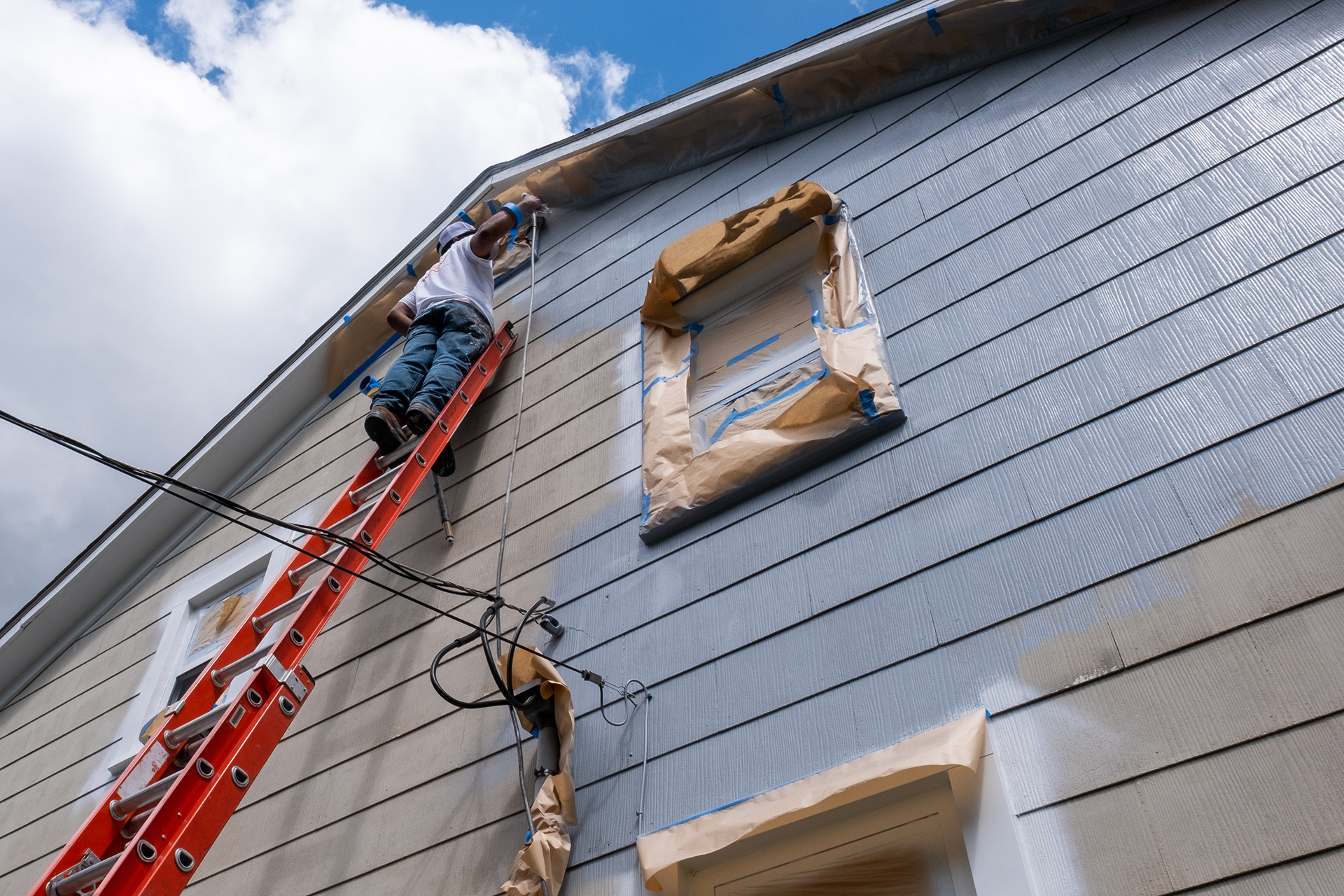 Detail view of painter working on gable trim under ladder