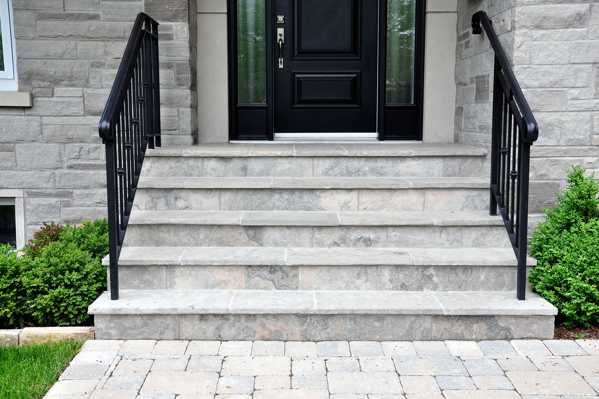 Natural stone front steps with black metal railing